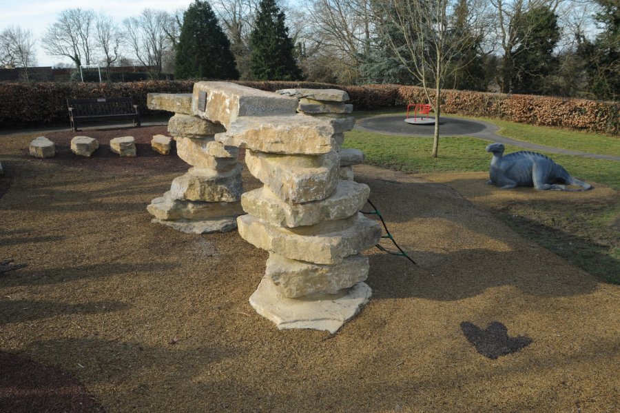 Cuckfield Iguanodon bronze sculpture behind a rock sculpture