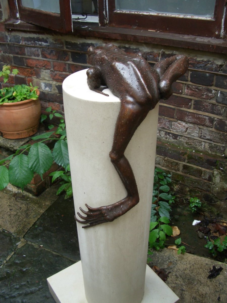 A bronze sculpture of a frog on a pillar